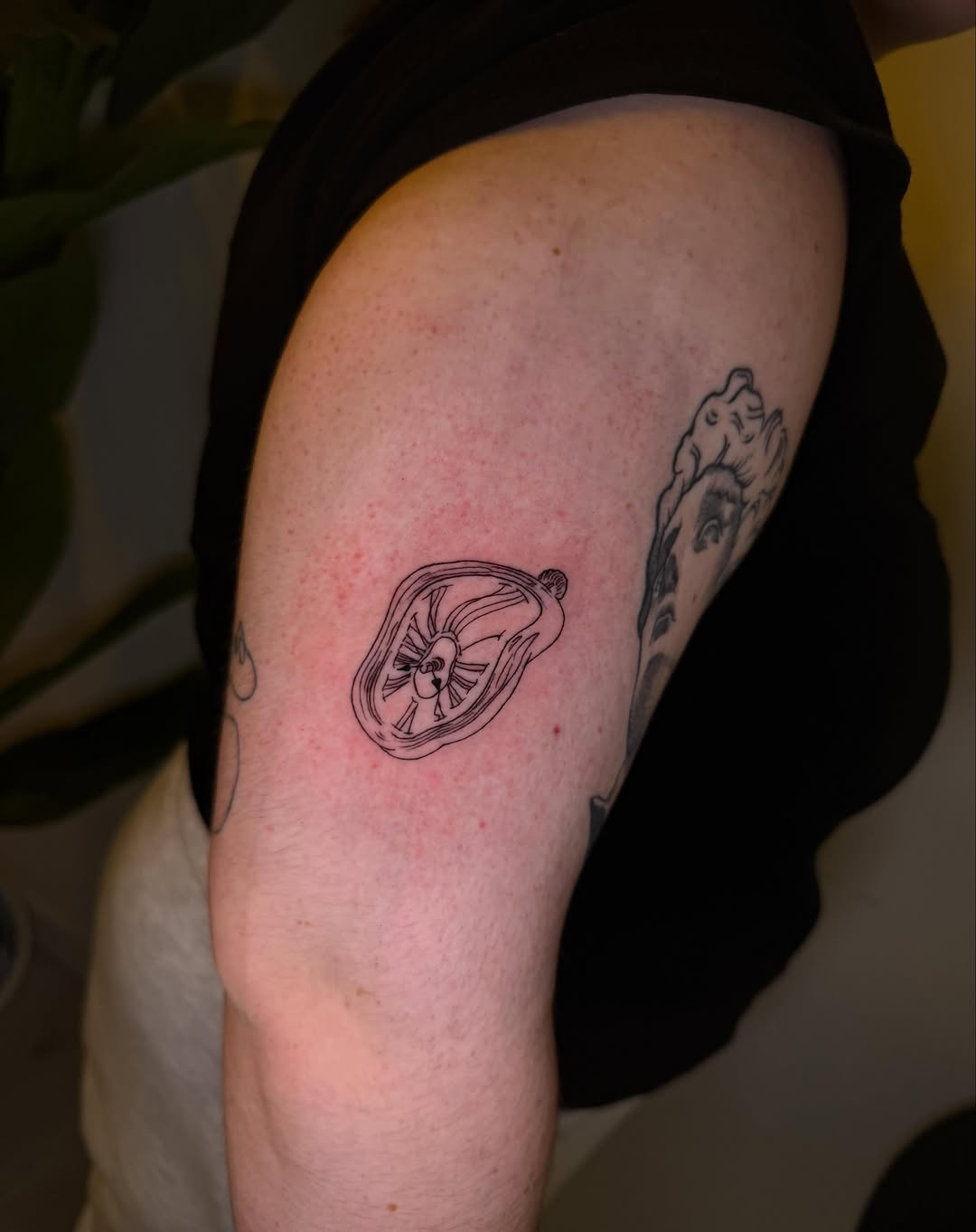 Tatuaje fine line reloj de Dalí en brazo
